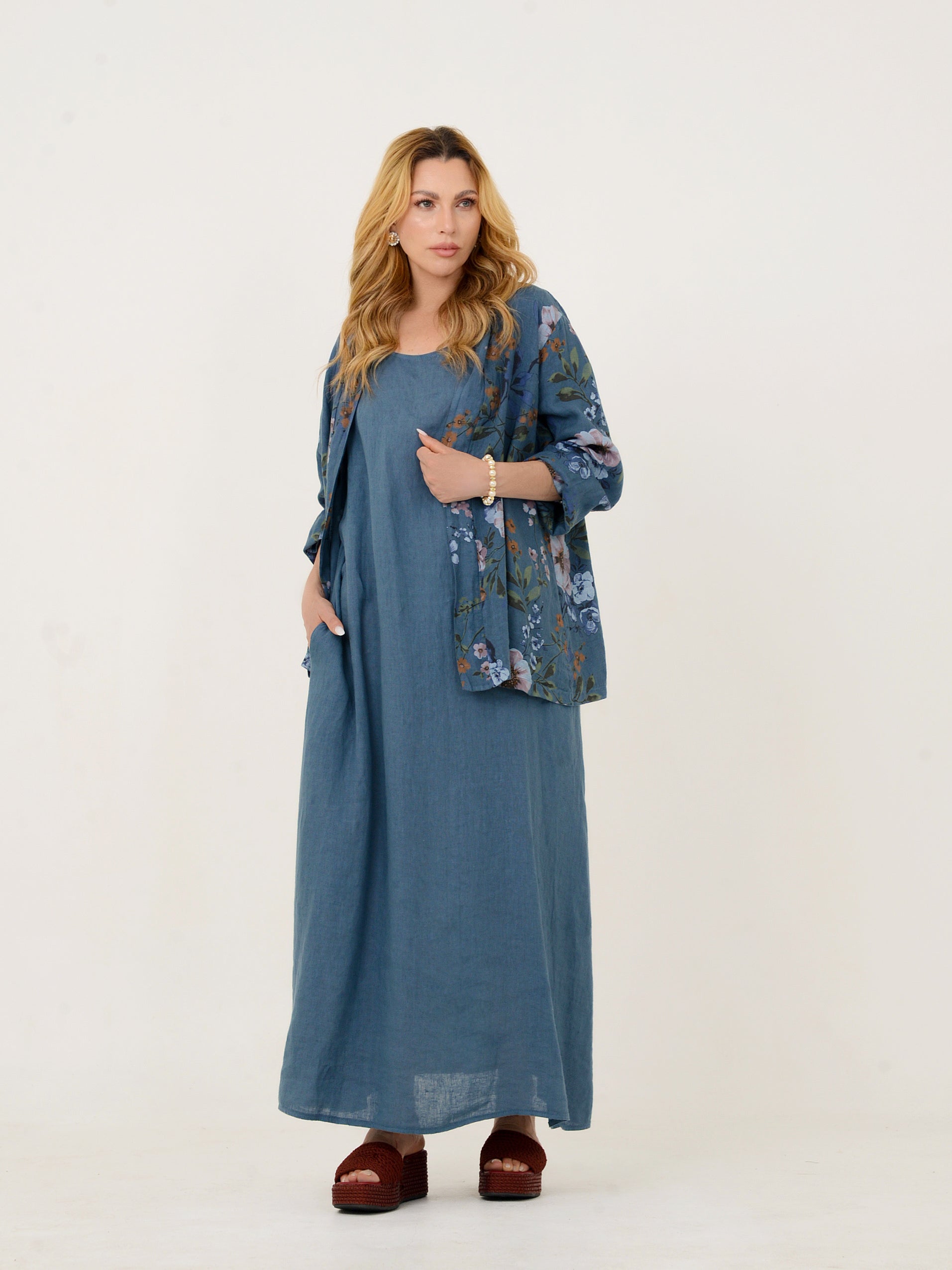 Modelo usando vestido longo azul de linho italiano com casaco bordado, vista frontal.