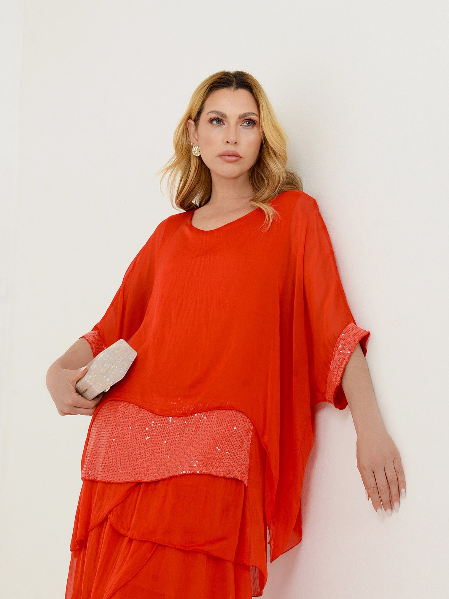 Detalhe do vestido vermelho em camadas com aplicação bordada.