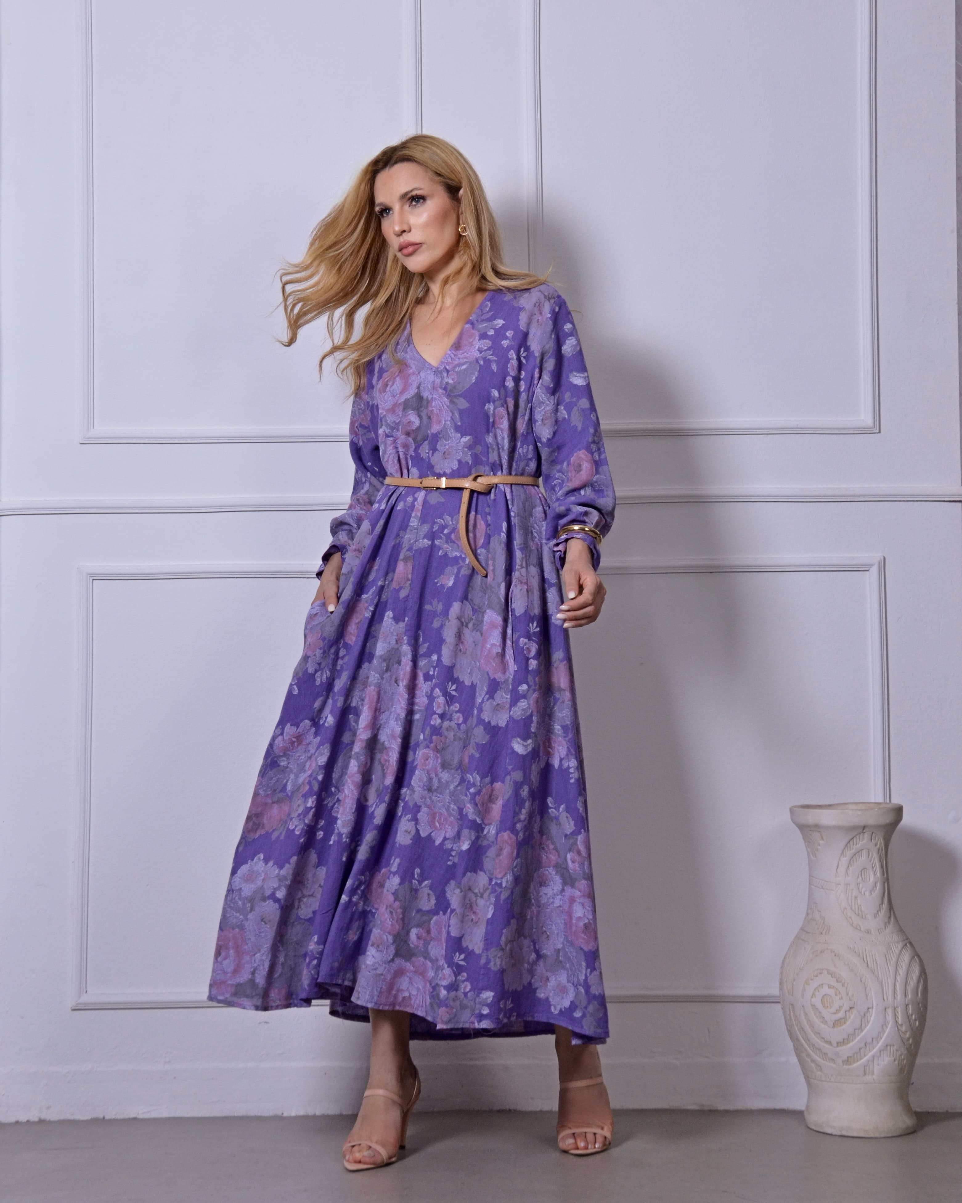 Mulher usando vestido longo roxo estampado com cintura marcada.